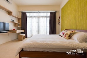A modern bedroom with a bed, a TV, and a shelf unit. - Wild Fun Hualien (Ji'an)