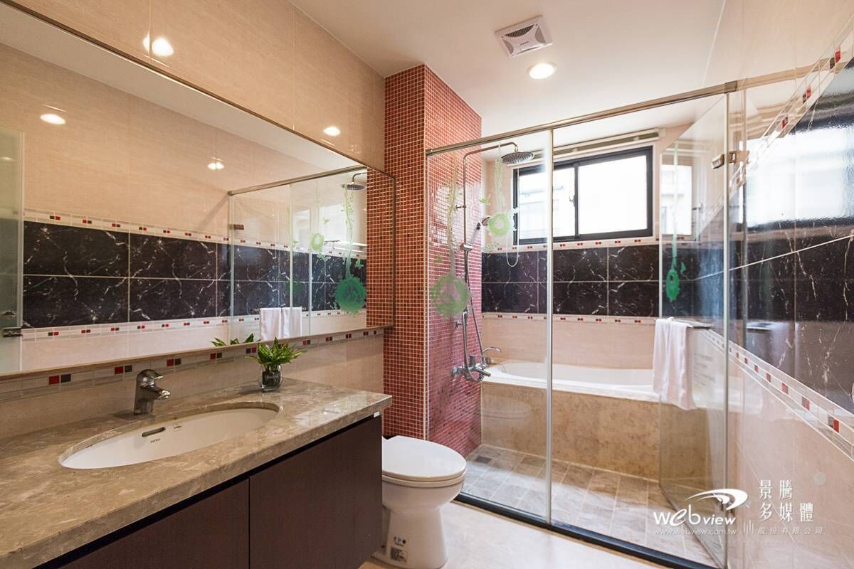 A modern bathroom with a large mirror, two sinks, a toilet, and a glass-enclosed shower area.