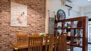 A dining area with a brick wall, wooden dining table, chairs, and a hanging light fixture. - Wild Fun Hualien (Ji'an)
