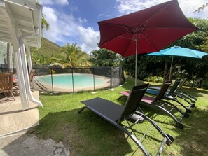 A backyard with a pool, lounge chairs, and umbrellas. - Villa with private lagoon pool - Tropical garden & absolute calm in Le Diamant (Le Diamant)