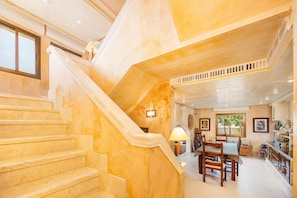 A staircase with a handrail, a dining area with a table and chairs, and a kitchen area with cabinets and a countertop. - Villa "Cala Llamp" with Panoramic Sea Views (PORT ANDRATX)