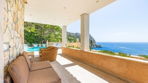 A balcony with a view of the sea, a pool, and a stone wall. - Villa "Cala Llamp" with Panoramic Sea Views (PORT ANDRATX)