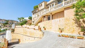 A multi-story building with a stone facade, a staircase leading to the upper floors, and potted plants along the pathway. - Villa "Cala Llamp" with Panoramic Sea Views (PORT ANDRATX)