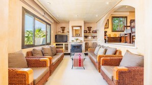 A spacious living area with wicker sofas, a central coffee table, and a fireplace. - Villa "Cala Llamp" with Panoramic Sea Views (PORT ANDRATX)
