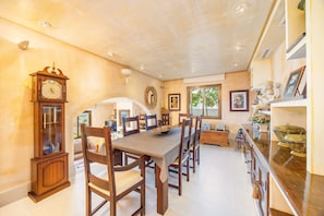 A dining area with a long table, wooden chairs, a grandfather clock, and a large mirror on the wall. - Villa "Cala Llamp" with Panoramic Sea Views (PORT ANDRATX)