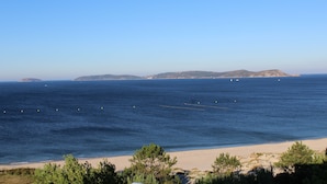 A coastal landscape with a sandy beach, clear blue sky, and distant hills. - Hotel Mar Azul (Sanxenxo)