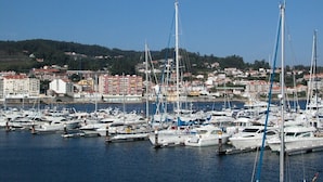 A marina with numerous boats docked, a clear sky, and a town in the background. - Hotel Mar Azul (Sanxenxo)