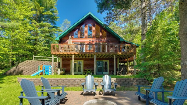 A log cabin with a balcony, surrounded by trees, and featuring outdoor seating and a fire pit. - Lakefront Hazelhurst Cabin: Dock & Pool Table (Hazelhurst)