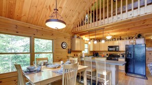 A wooden cabin interior with a dining area, kitchen, and a loft bedroom. - Lakefront Hazelhurst Cabin: Dock & Pool Table (Hazelhurst)