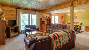 A cozy log cabin interior with a living room featuring two sofas, a coffee table, and a television. - Lakefront Hazelhurst Cabin: Dock & Pool Table (Hazelhurst)