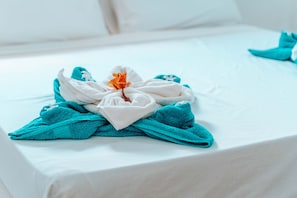 A neatly made bed with a towel and a flower on it. - Simba Apartment Hotel (Bwejuu)