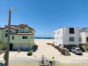 A coastal street with a two-story building, a parked car, and a clear view of the beach. - The Kid  - Ocean Front Beach House at Hollywood Beach (Oxnard)