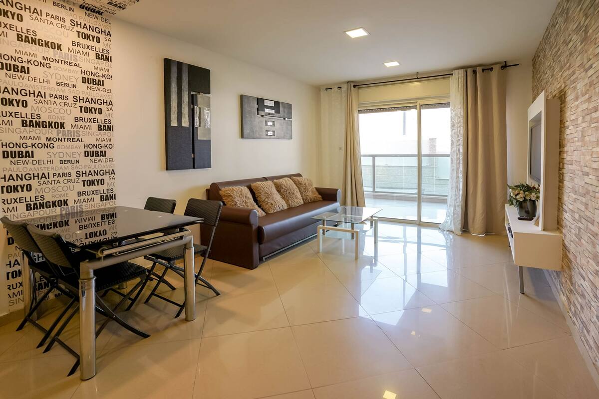 A modern living room with a sofa, a glass coffee table, and a dining table with chairs.