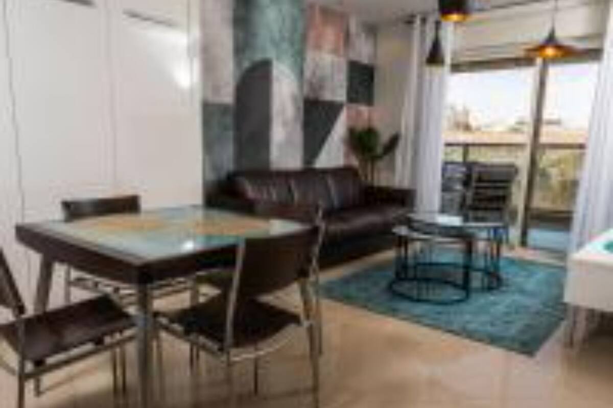 A modern living room with a dining area, a sofa, a coffee table, and a view through the window.