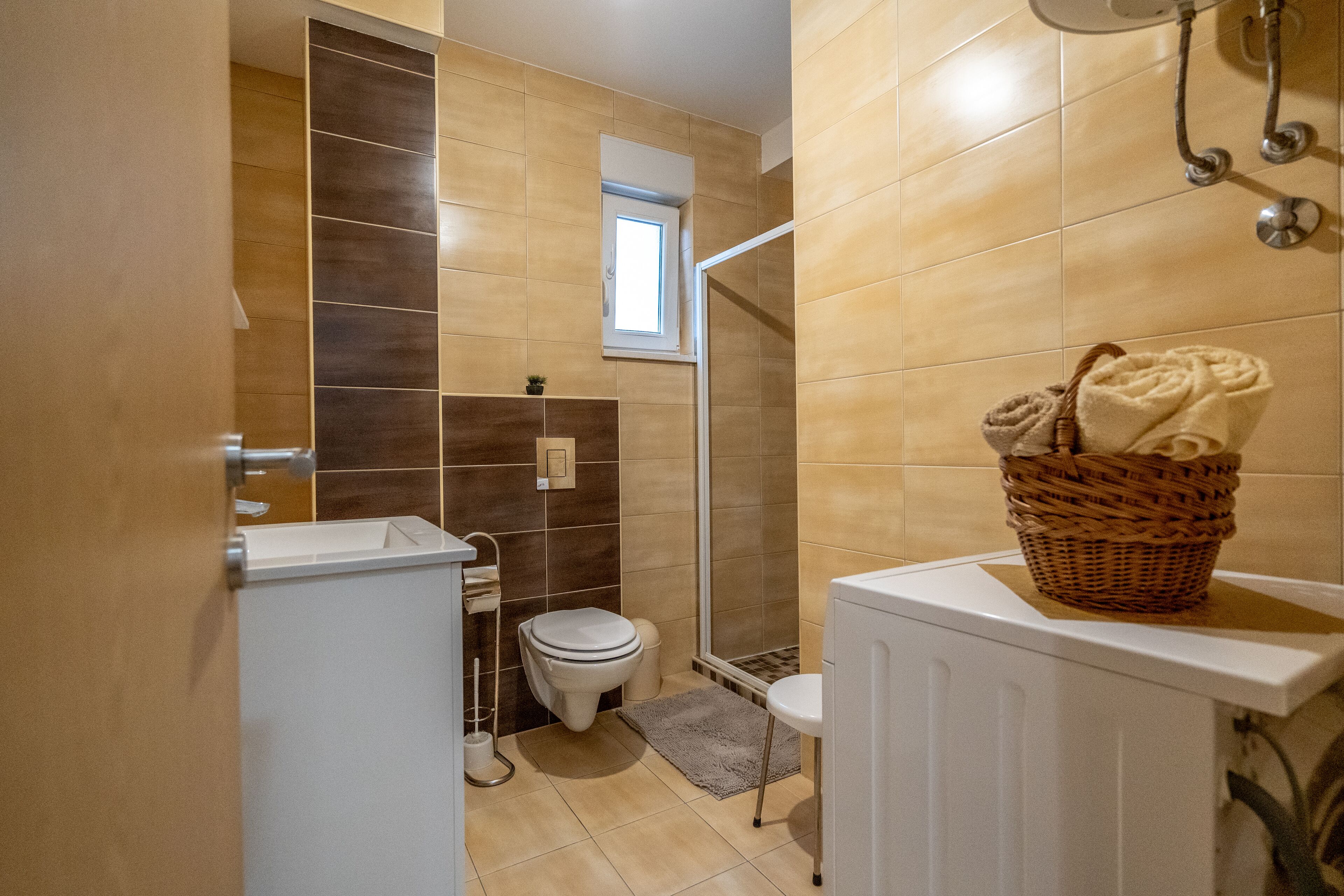 A bathroom with a shower, toilet, and a small window.