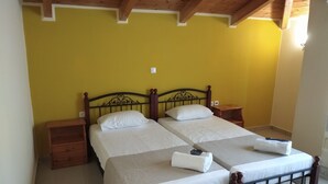 Una cama doble con cabecera de madera, dos mesitas de noche y una pequeña mesita auxiliar de madera.