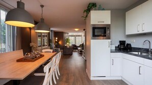 Una cocina moderna con armarios blancos, microondas integrado y un lavamanos de acero inoxidable.