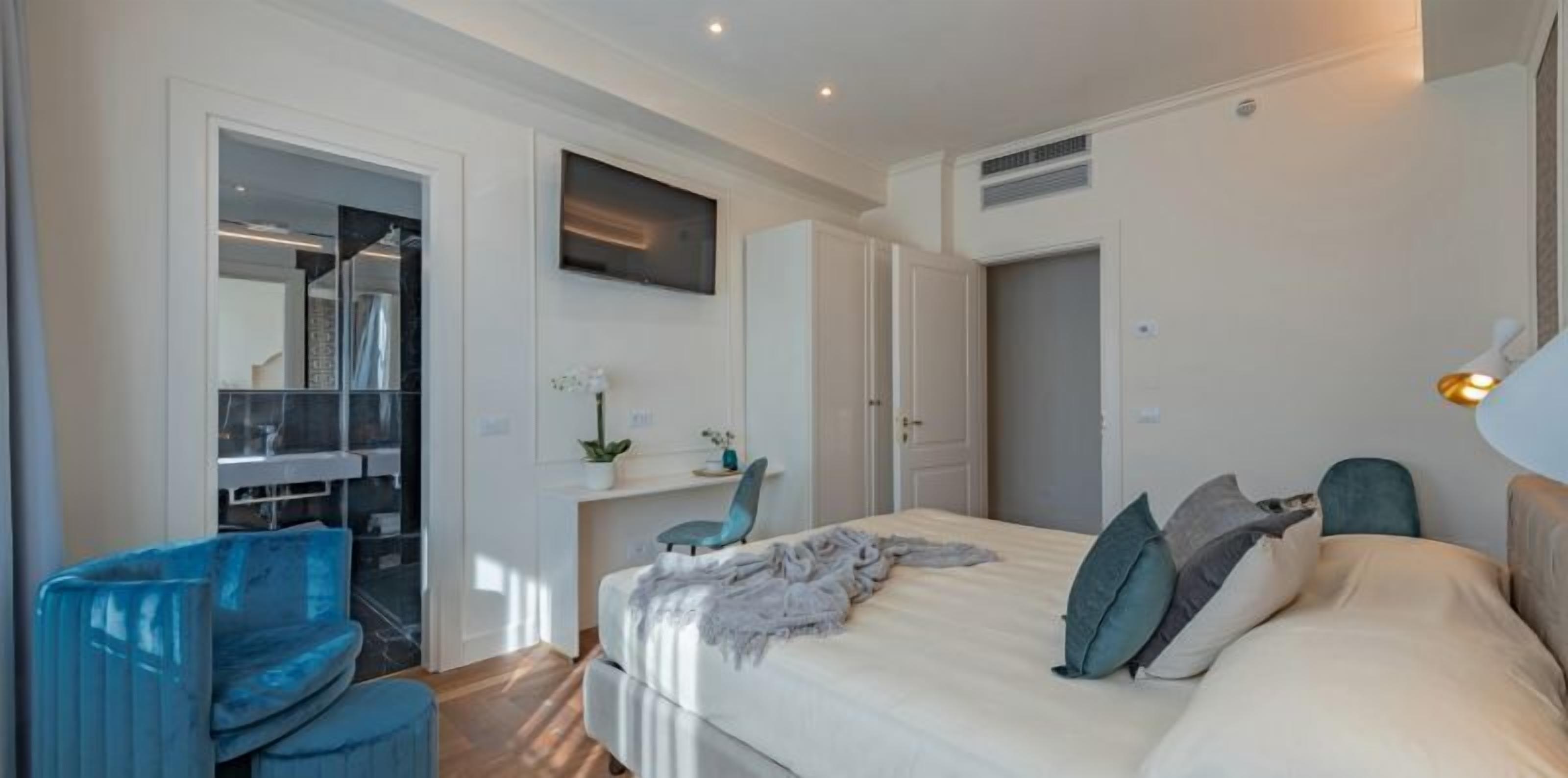 Quarto moderno com cama, escrivaninha e cadeira. Há também um guarda-roupa e um espelho.
