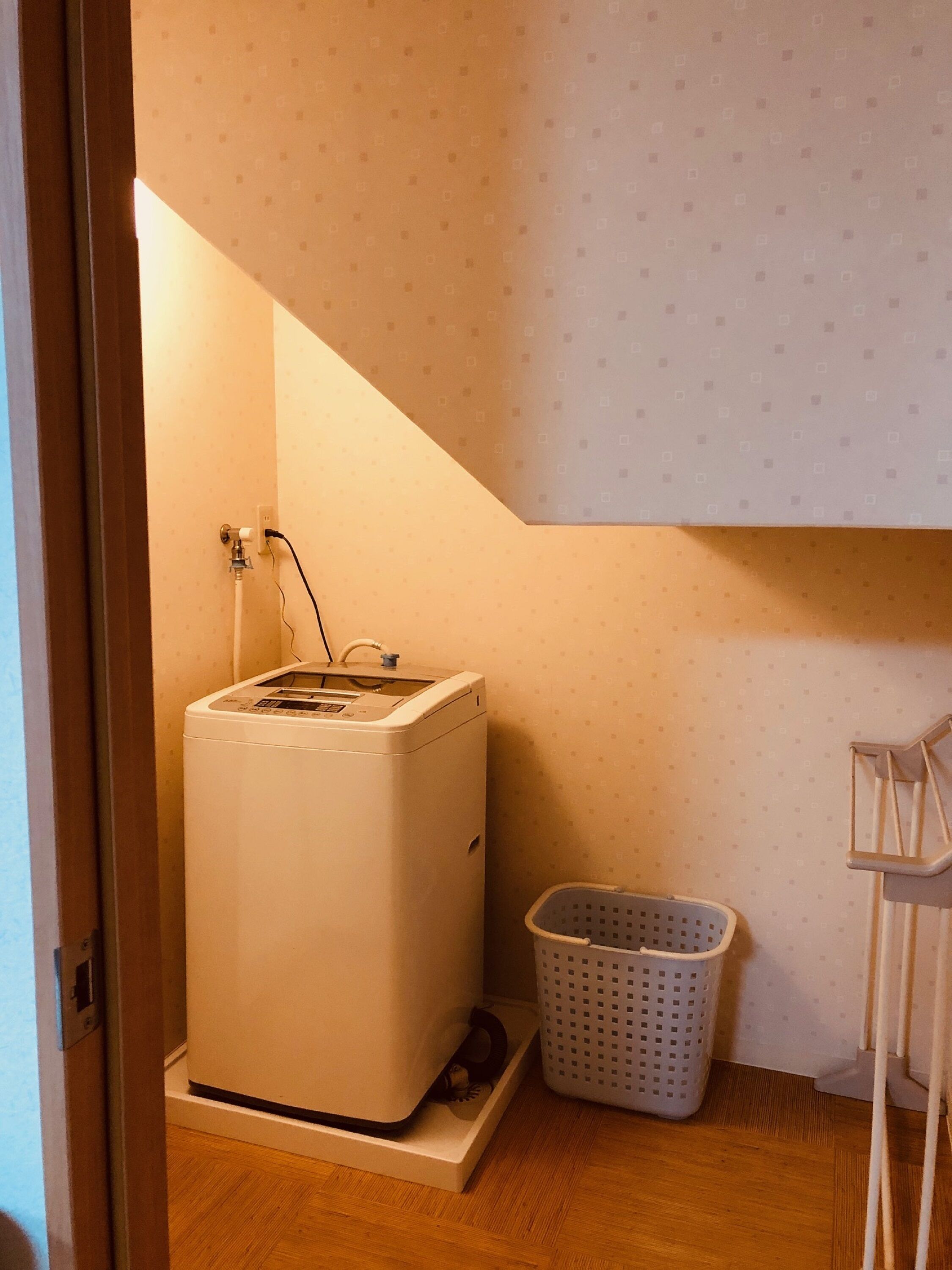A compact laundry room with a washing machine, a drying rack, and a laundry basket.
