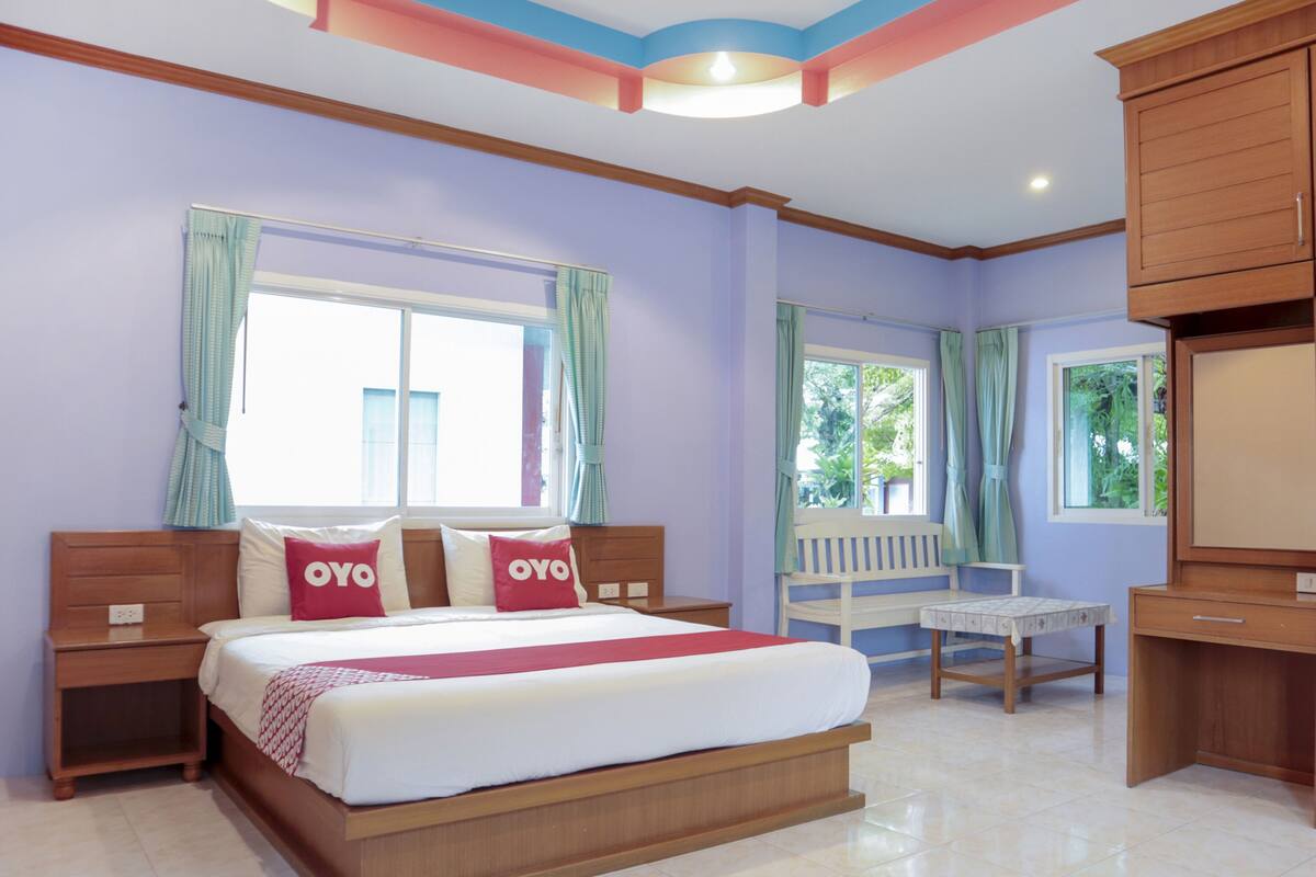 A bedroom with a large bed, bedside tables, a small table, and a TV.