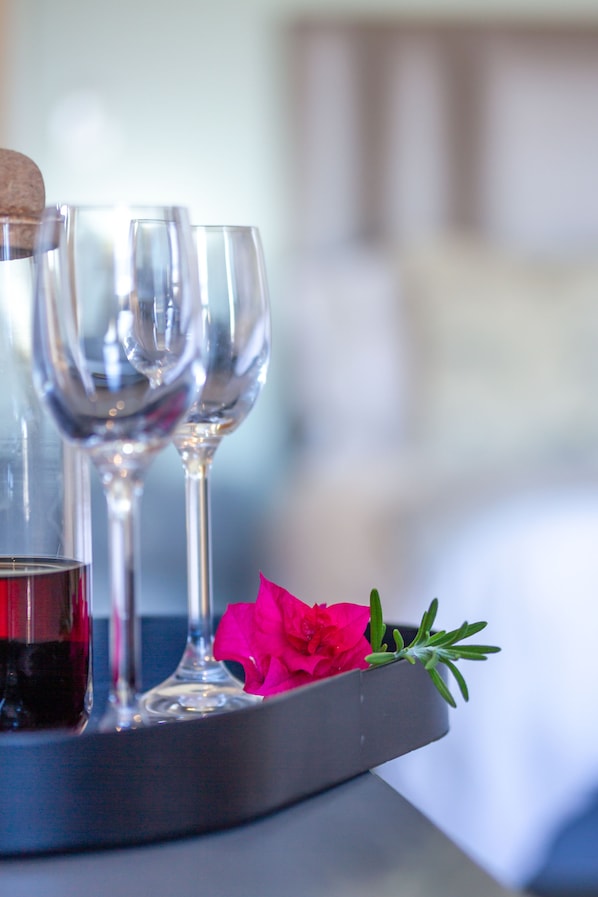 A tray with three wine glasses, one with red wine, and a pink flower with green leaves. - Chateau de Marine (Struisbaai)