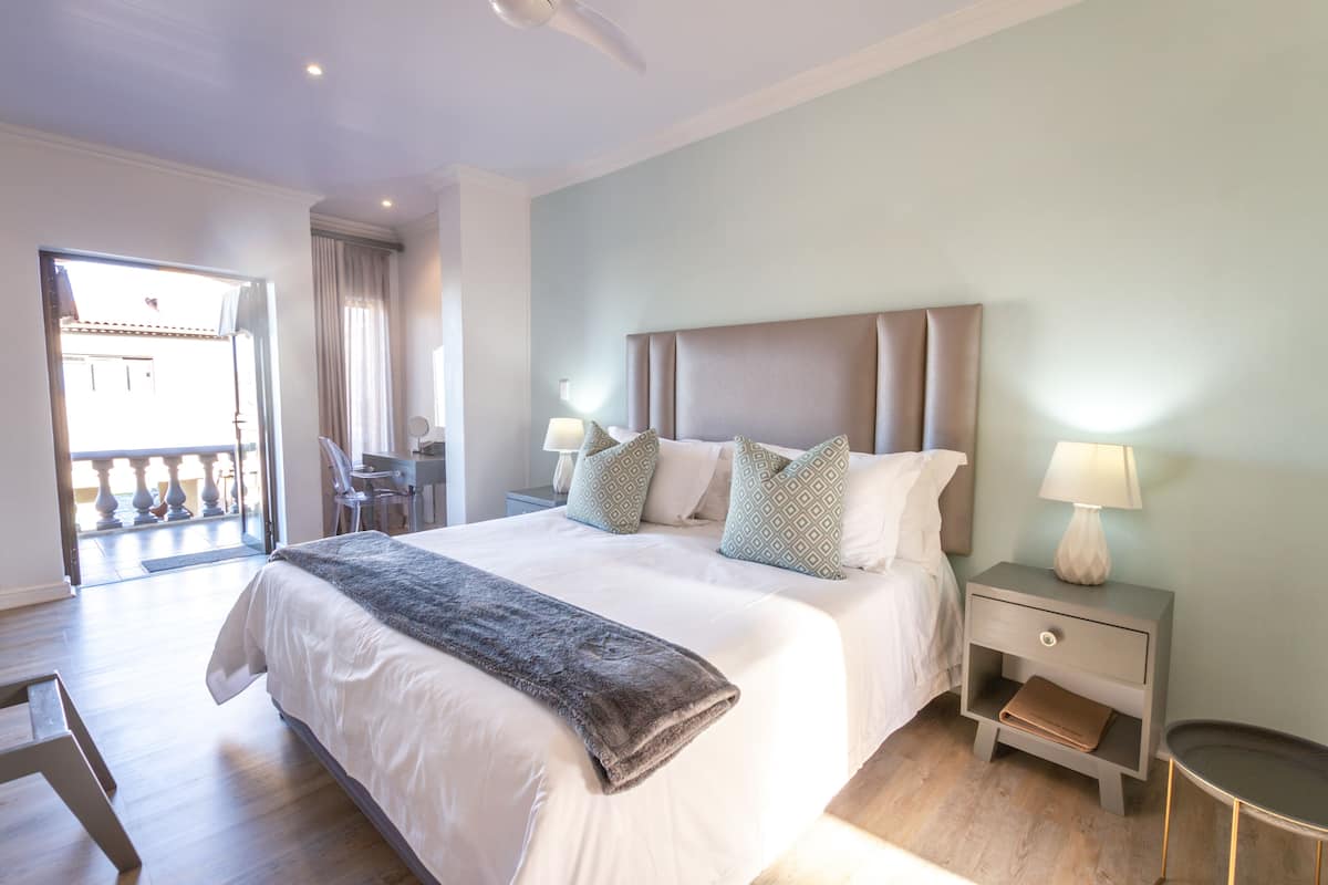 Une chambre bien aménagée, avec un grand lit, des tables de chevet et une vue sur le balcon extérieur.