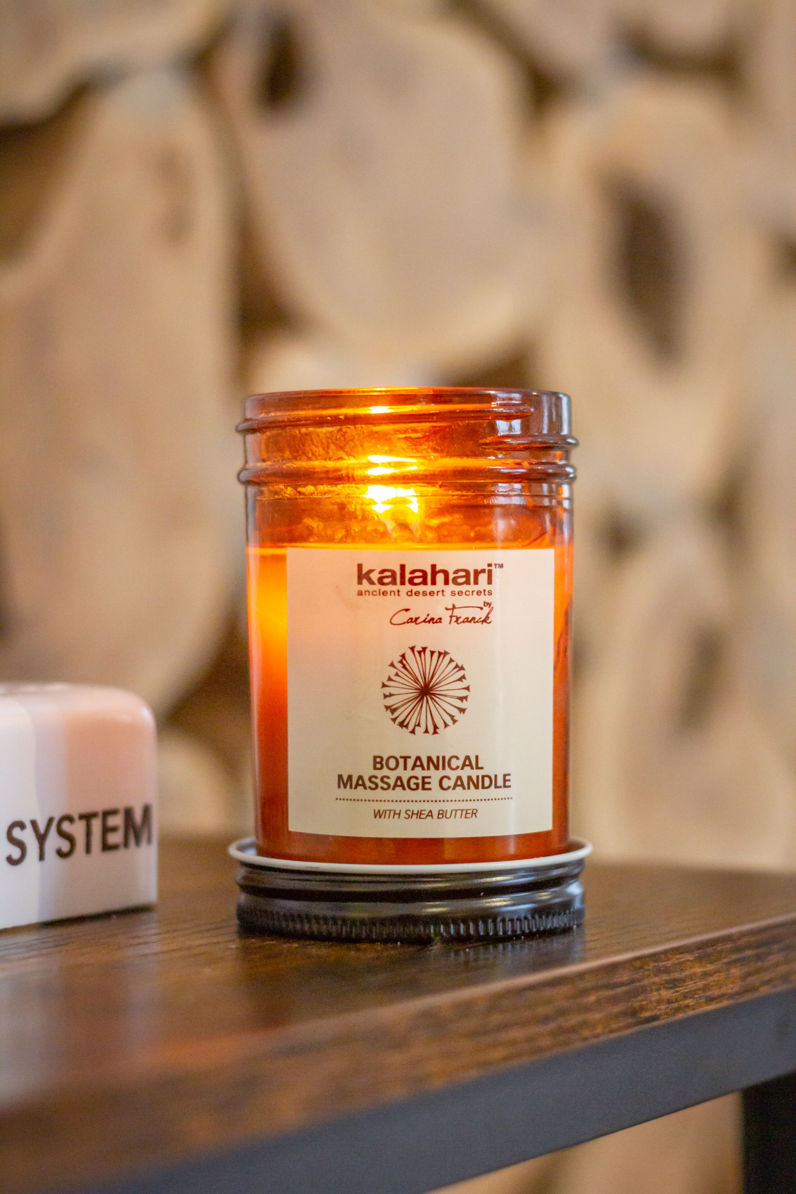 A candle labeled "kalahari" with a botanical massage candle and shea butter.