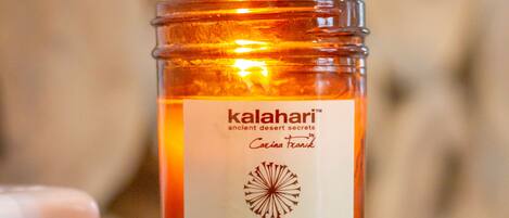 A candle labeled "kalahari" with a botanical massage candle and shea butter.