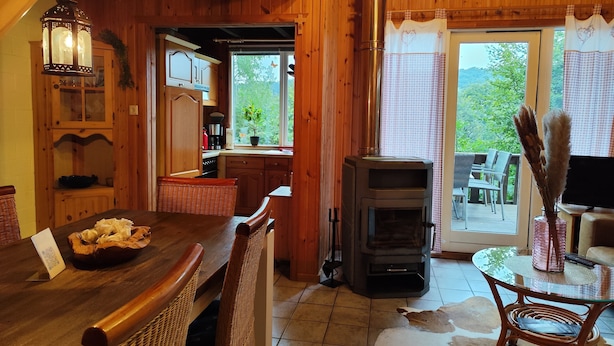 Un intérieur chaleureux, avec des murs en bois, comprenant un coin repas, une cuisine et un poêle à bois.