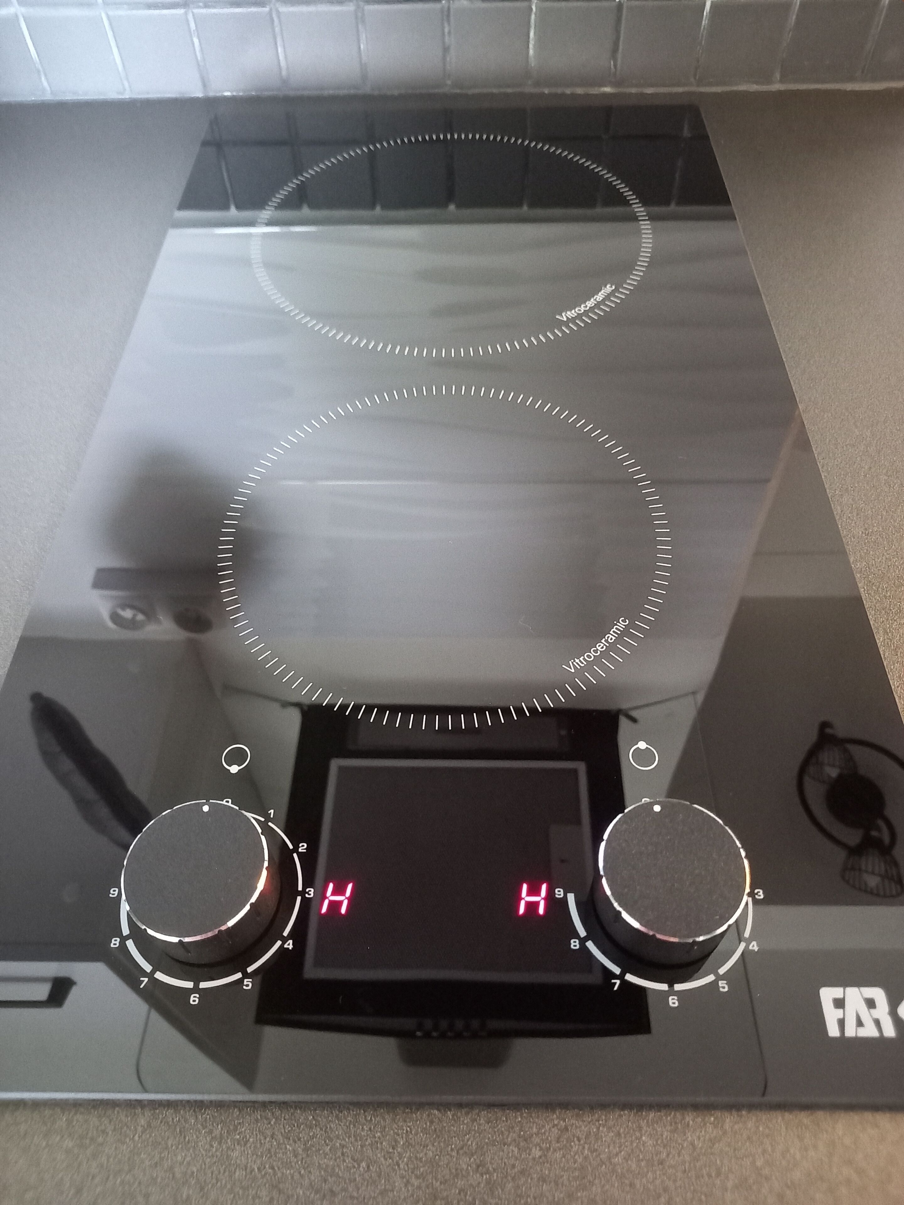 Eine Küche mit einer digitalen Kochplatte, zwei Bedienelementen und einem digitalen Display.
