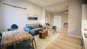 A modern living room with a wooden dining table, a grey sofa, and a patterned rug. - Apartments Florence Oblate Exclusive (Florence)