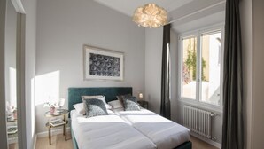 A modern bedroom with a large bed, a bedside table with a lamp, a framed artwork on the wall, and a window with curtains. - Apartments Florence Oblate Exclusive (Florence)