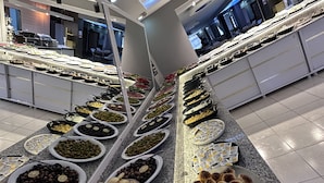 Un bufé con diversos alimentos, como aceitunas, pan y otros platos, dispuesto sobre una encimera de granito.