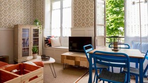 A cozy room with a wooden desk, a television, and blue chairs.