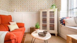 A cozy living room with a red sofa, a white cabinet with glass doors, and a small round table with decorative items.