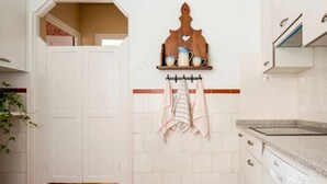 A kitchen with white cabinets, a wooden shelf with cups, and a towel rack.