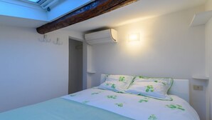 A bedroom with a bed, an air conditioning unit, and a skylight. - Apartments Florence - San Lorenzo Market (Florence)