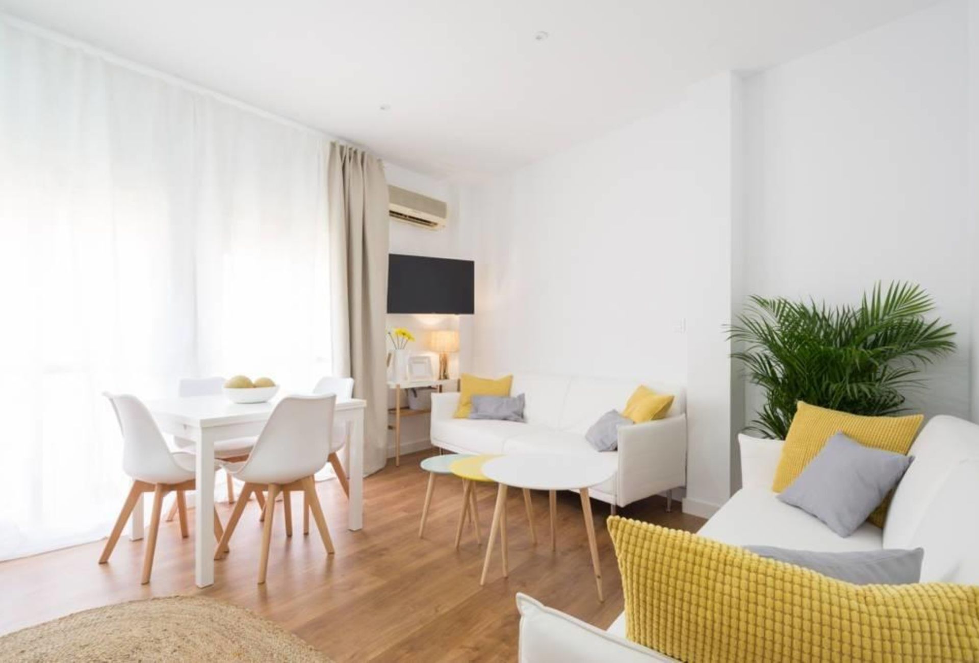 Een moderne woonkamer met een eethoek, witte meubels en een grote plant.
