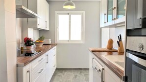 Una cocina moderna con armarios blancos, encimera de madera, ventana y una lámpara colgante.