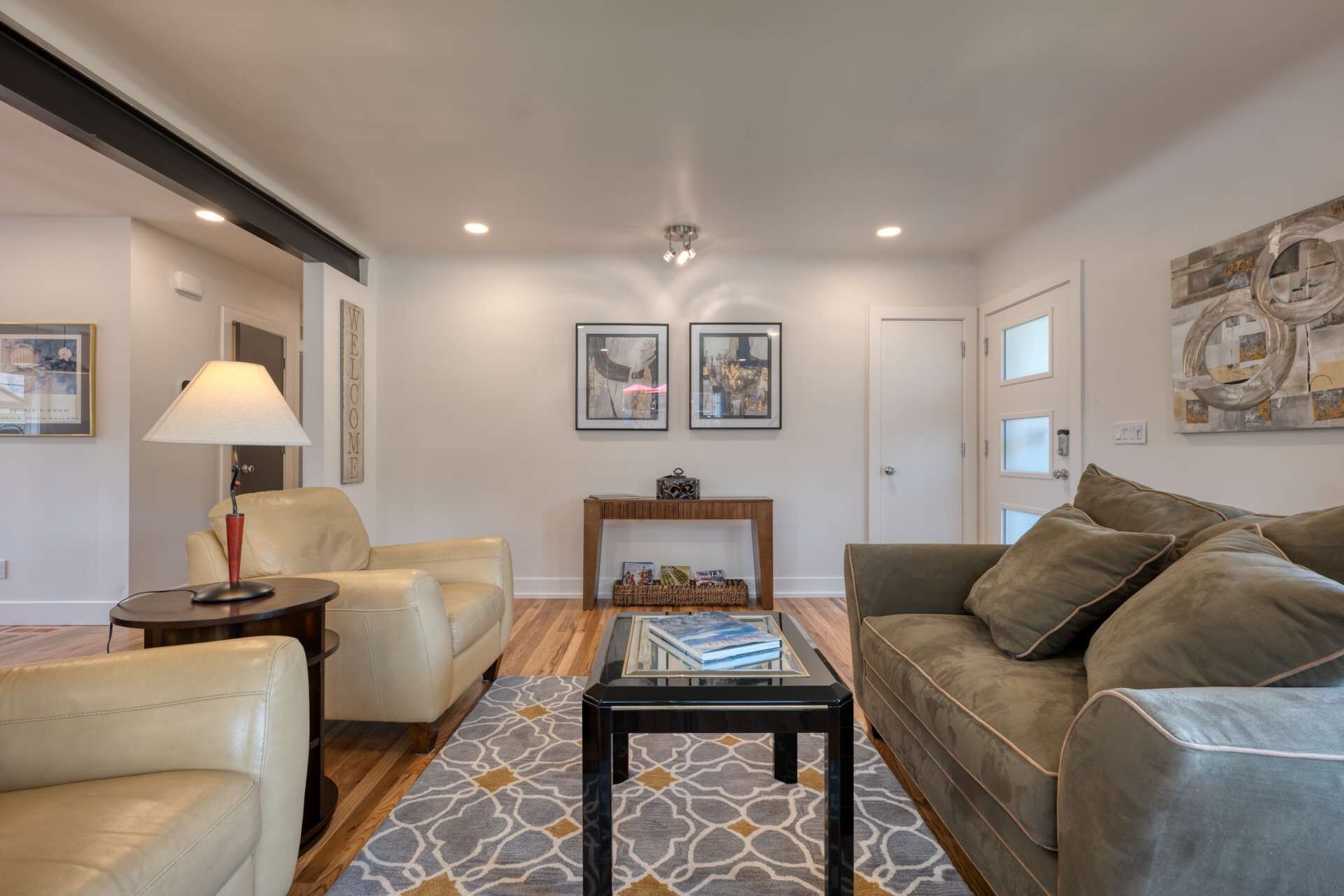A living room with a beige sofa, a brown sofa, a coffee table, a lamp, and framed pictures on the wall.