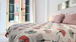 Een slaapkamer met een groot bed, een raam met luiken en een spiegel aan de muur.