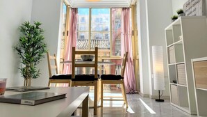 Een moderne woonkamer met een eetgedeelte, grote ramen en uitzicht op een historisch gebouw.