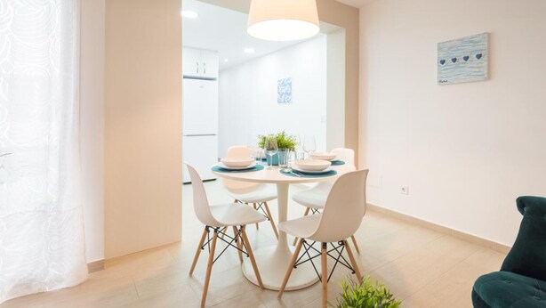 Un comedor con una mesa redonda, sillas blancas y una lámpara colgante.
