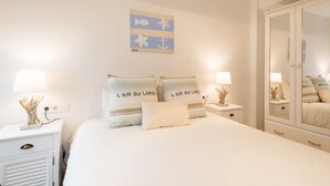 Un dormitorio con una cama, dos mesitas de noche, un espejo y un adorno en la pared.