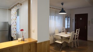 Una cucina funzionale con piano in legno, frigorifero e zona pranzo con tavolo e sedie.