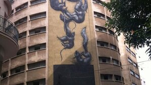 Un edificio con una facciata curva, numerosi balconi e un grande murale raffigurante un drago.