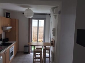 Eine kleine Küche mit Essbereich, einem Fenster und einem Mülleimer.