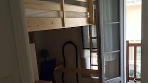 Une chambre avec un lit superposé, un bureau, une chaise et une fenêtre.