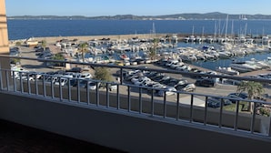 A marina with boats and cars, a clear sky, and a distant view of hills. - 4-person apartment facing the sea 50m from the beach and town center (Sainte-Maxime)