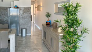 A modern kitchen with a marble herringbone floor, a stainless steel refrigerator, and a wooden cabinet with a helmet and a plant on top. - 4-person apartment facing the sea 50m from the beach and town center (Sainte-Maxime)